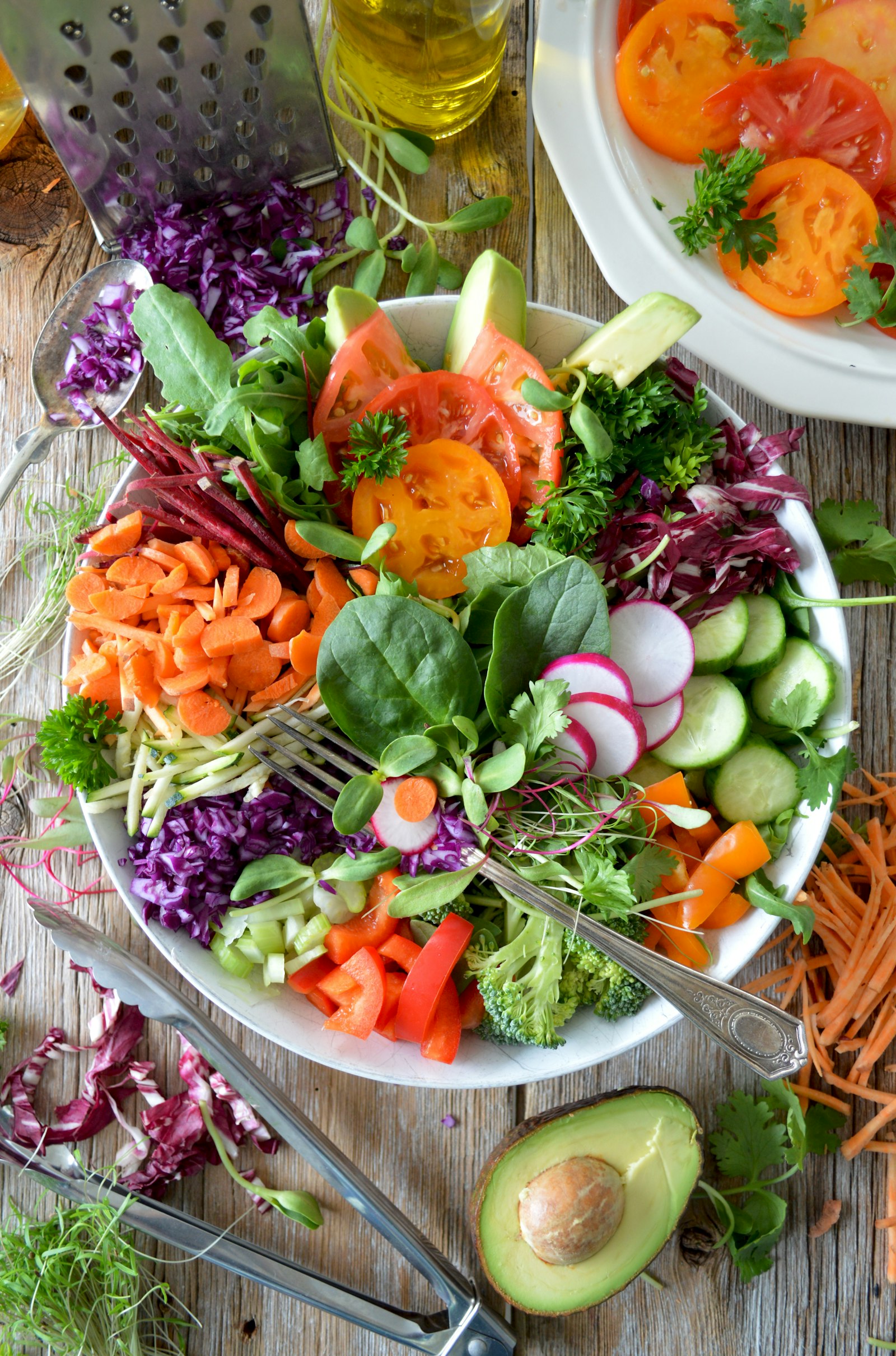 Colorful bowl of fresh vegetables including tomatoes, spinach, cucumbers, carrots, and avocado - all naturally gluten-free